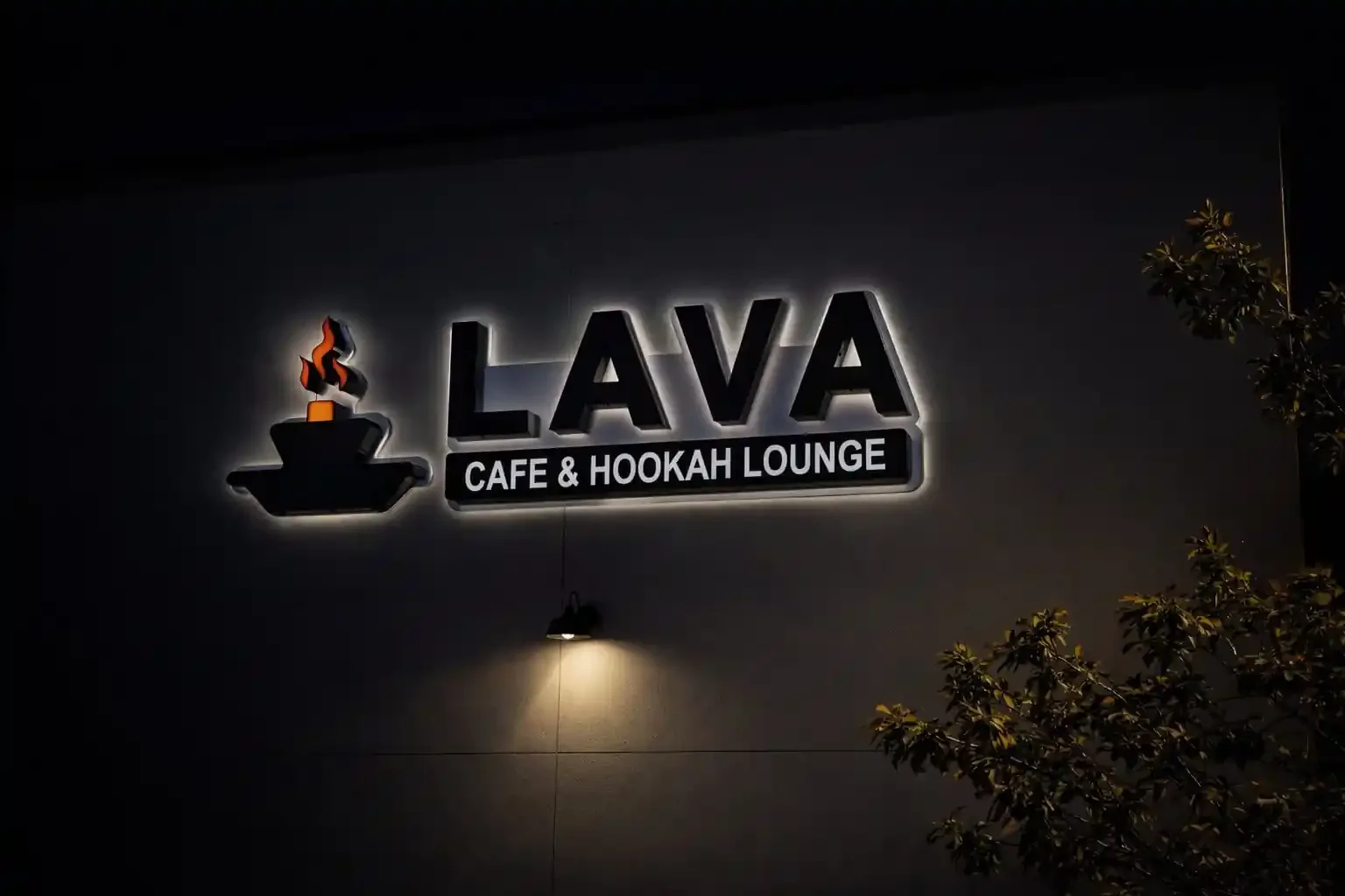 LAVA Cafe and Hookah Lounge backlit exterior sign glowing at night. The mark and wordmark are rendered as dimensional letters against a dark sky.
