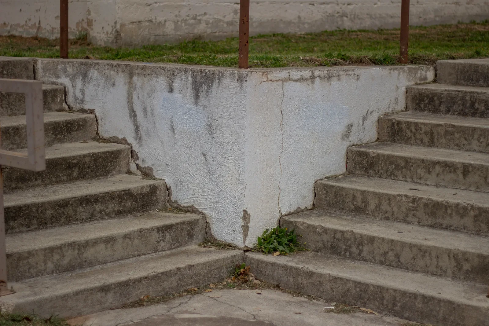 Two flights of weathered concrete steps meeting at an inside corner, framed so the two flights appear to occupy the same plane